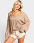 Woman wearing a beige sweater and white shorts on a light gray background