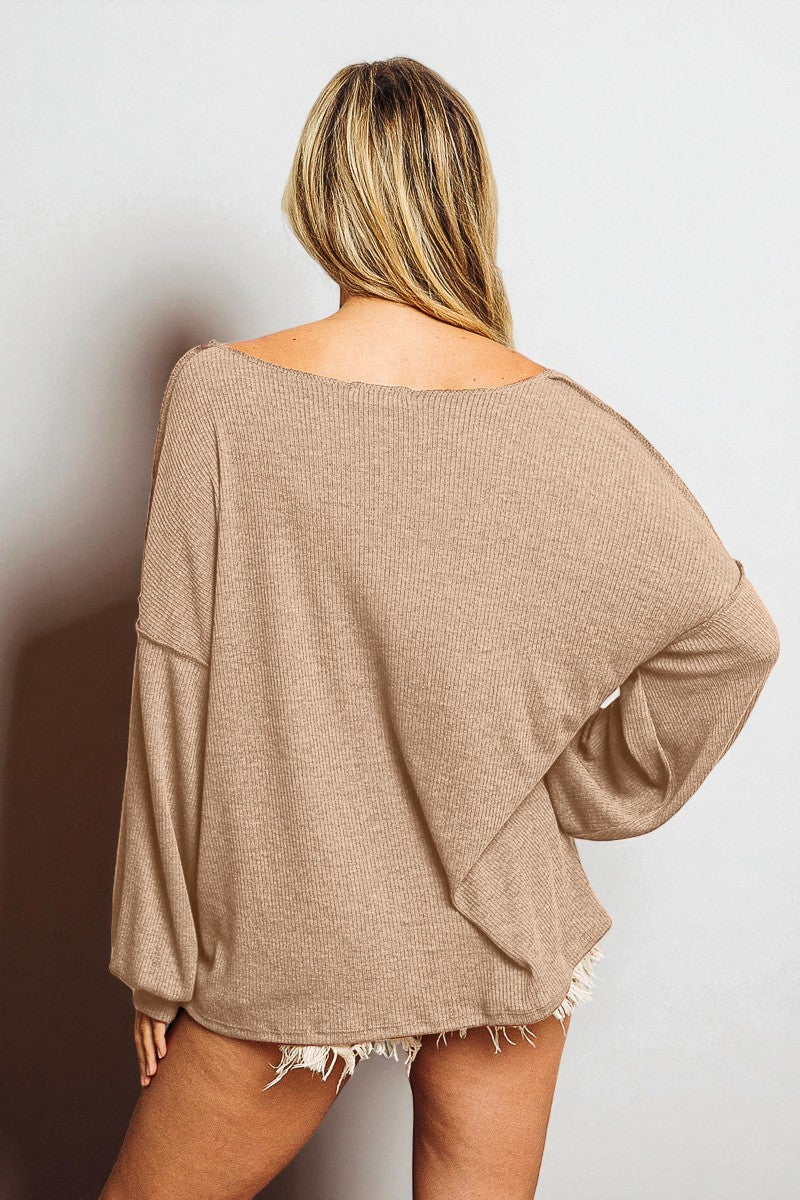 Person wearing a beige oversized sweater against a plain background