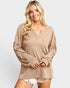 Woman wearing a beige sweater on a plain background