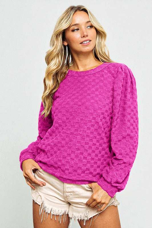 Woman wearing a bright pink sweater and white shorts on a light gray background