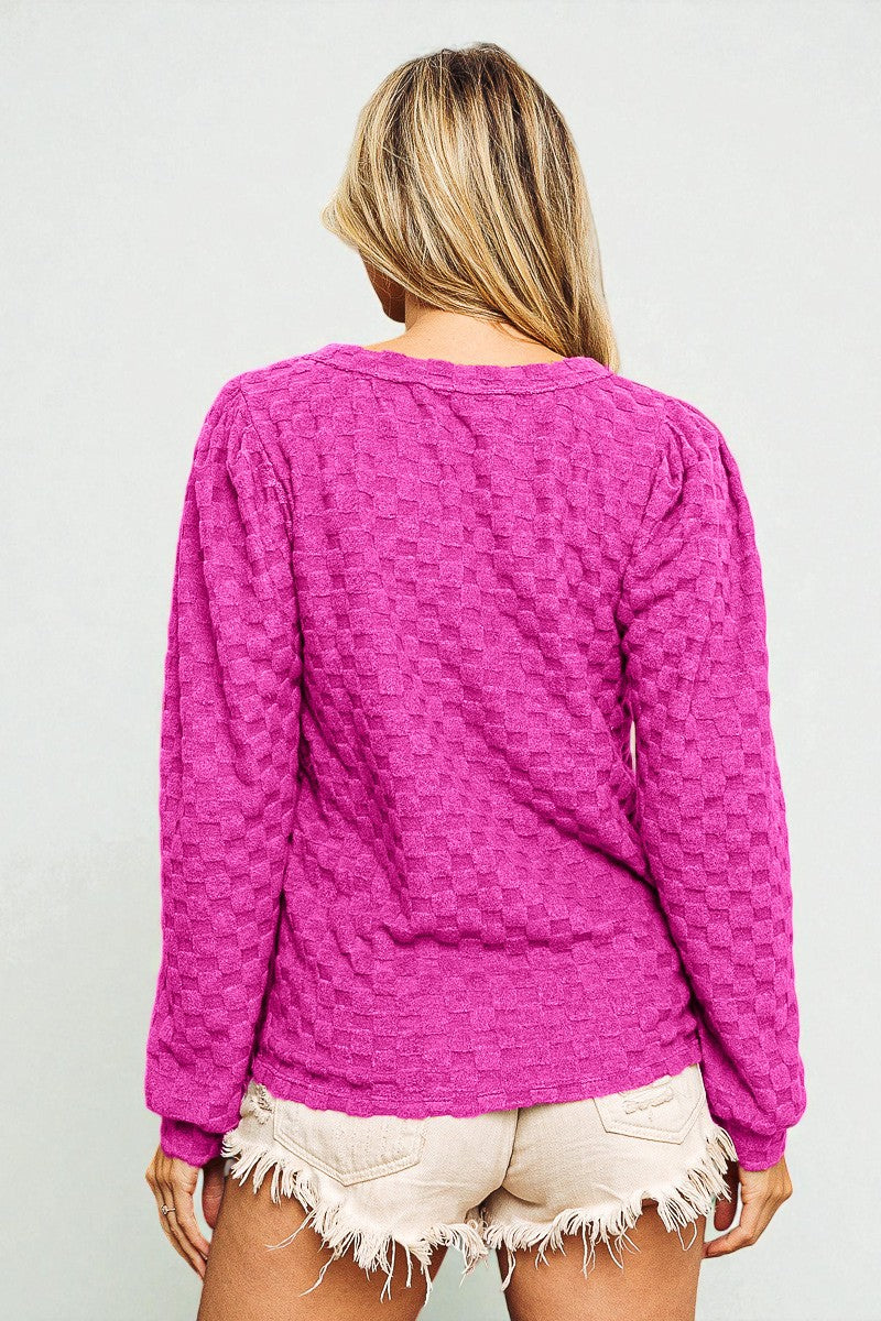 Person wearing a pink textured long-sleeve top against a plain background