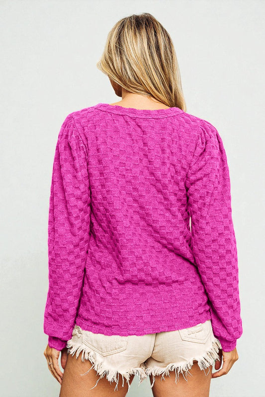 Person wearing a pink textured long-sleeve top against a plain background