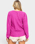 Person wearing a pink textured long-sleeve top and white shorts on a light gray background