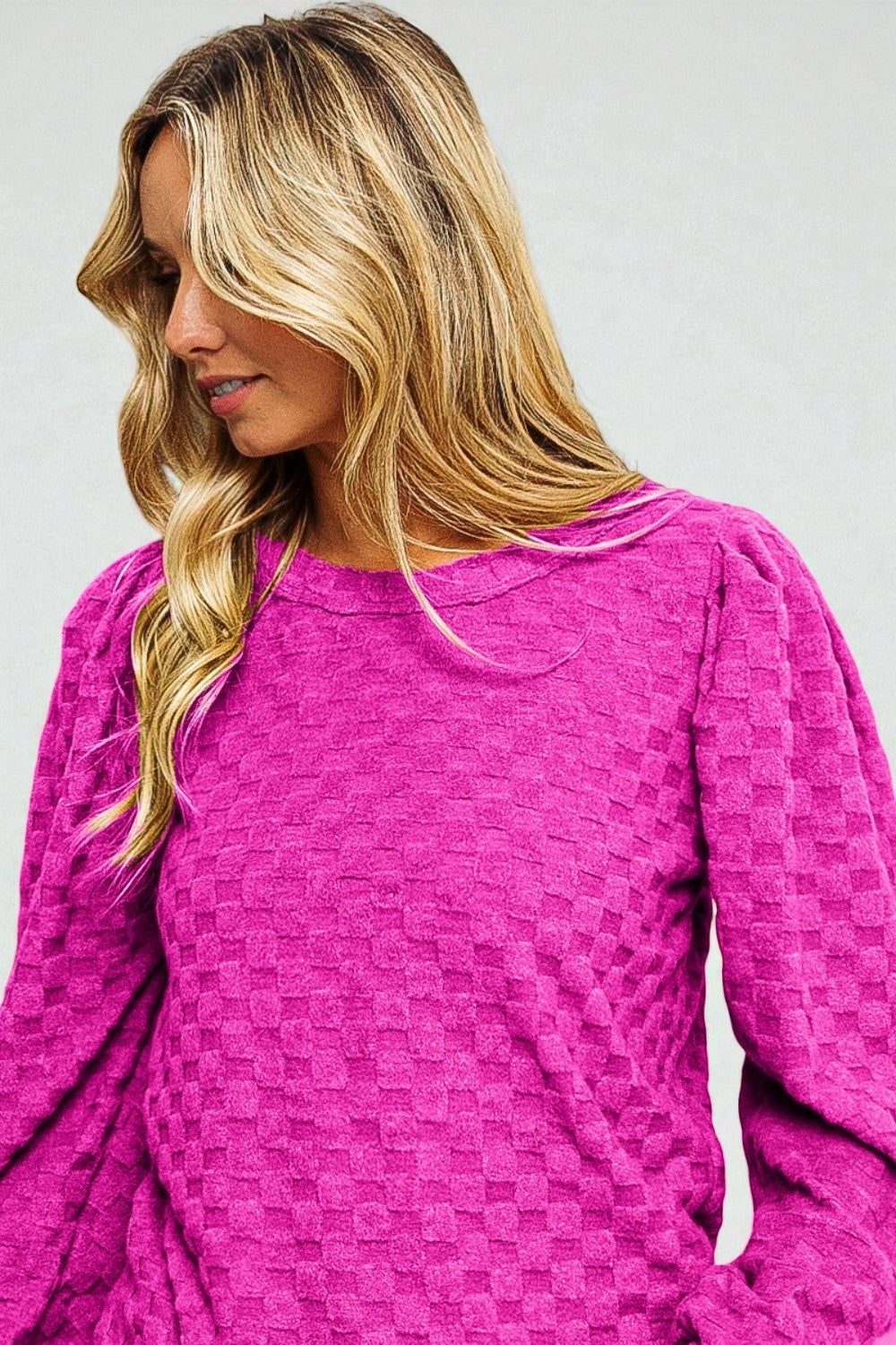 Woman wearing a pink textured dress against a plain background