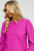 Woman wearing a pink textured dress against a plain background