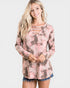 Woman wearing a long-sleeve, floral-patterned top with cut-out details on a white background