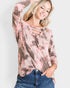 Woman wearing a tie-dye long-sleeve top with cut-out details on a plain background