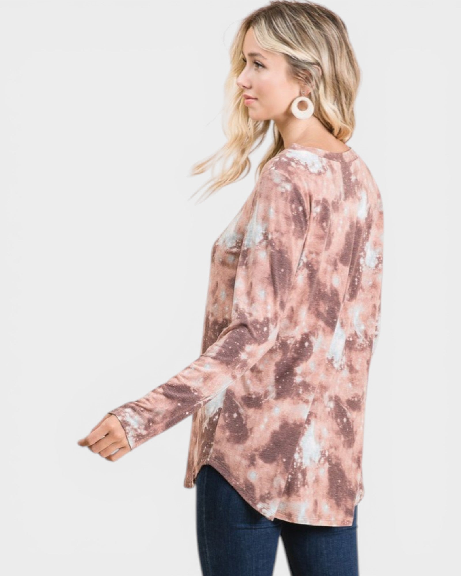 Woman wearing a long-sleeve, tie-dye shirt with a white background