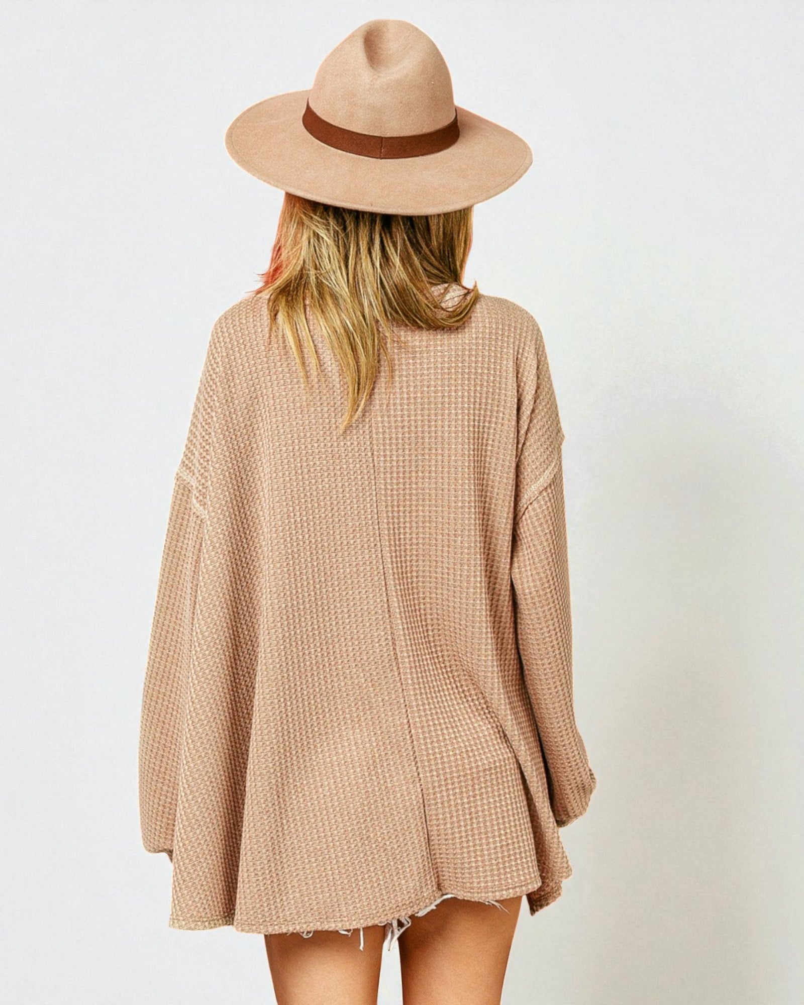 Person wearing a beige checkered dress and hat on a white background