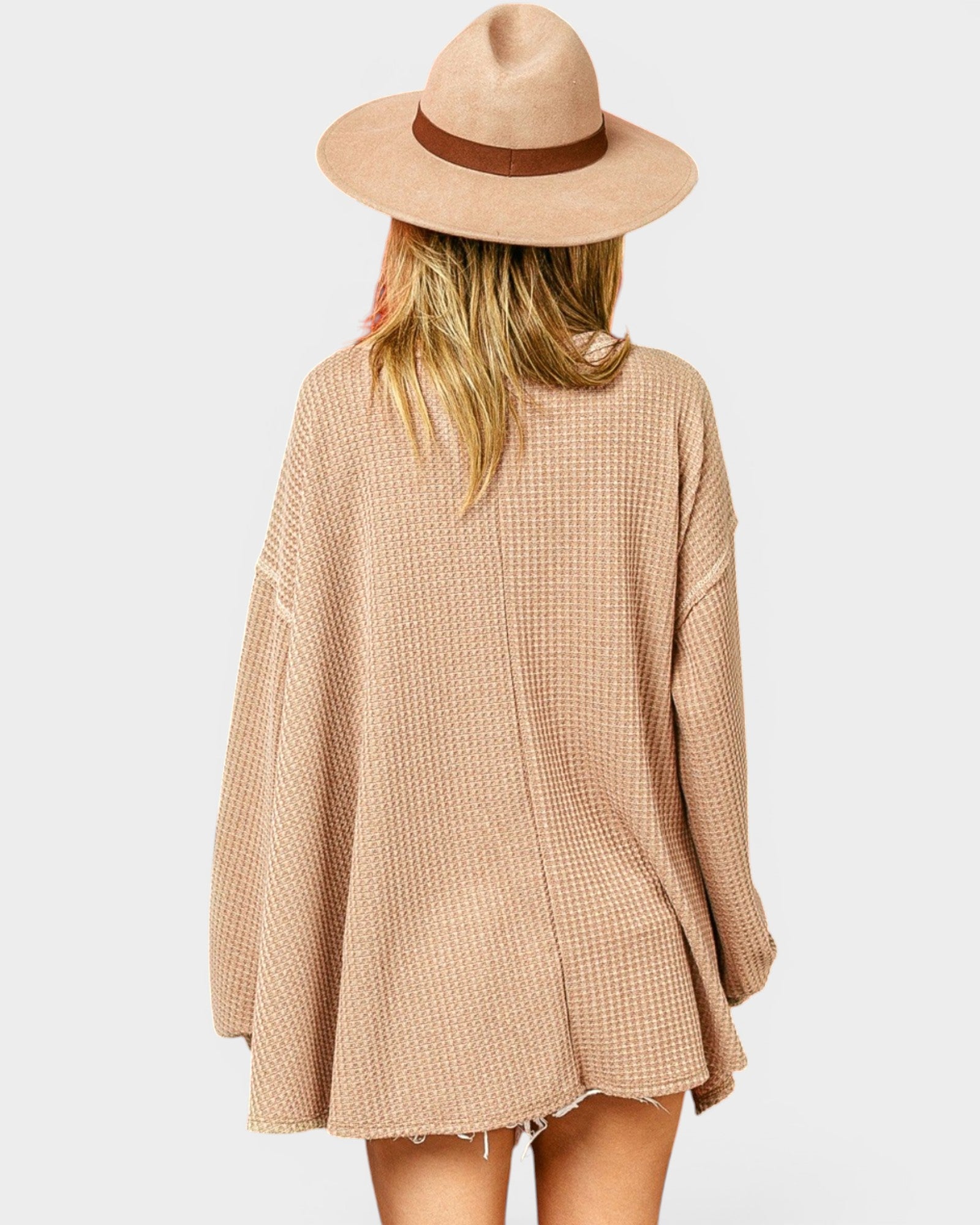 Person wearing a beige checkered dress and hat on a white background