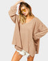 Woman wearing a beige oversized sweater and sunglasses on a white background