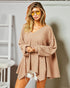 Woman wearing a beige oversized sweater and sunglasses indoors.
