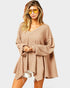 Woman wearing a beige oversized sweater with a plain background