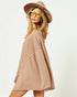 Woman wearing a beige dress and hat with yellow sunglasses on a white background