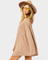Woman wearing a beige cardigan, sunglasses, and a brown hat on a white background