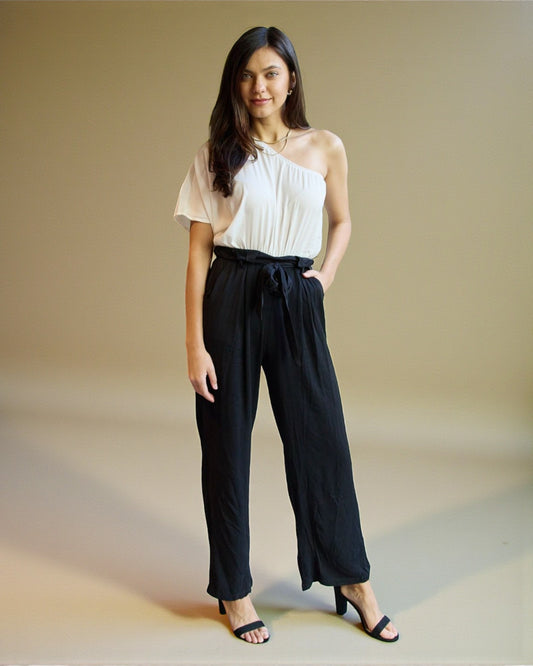 Woman wearing a white top and black pants against a beige background