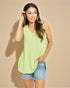 Woman wearing a light green sleeveless top and denim shorts on a beige background