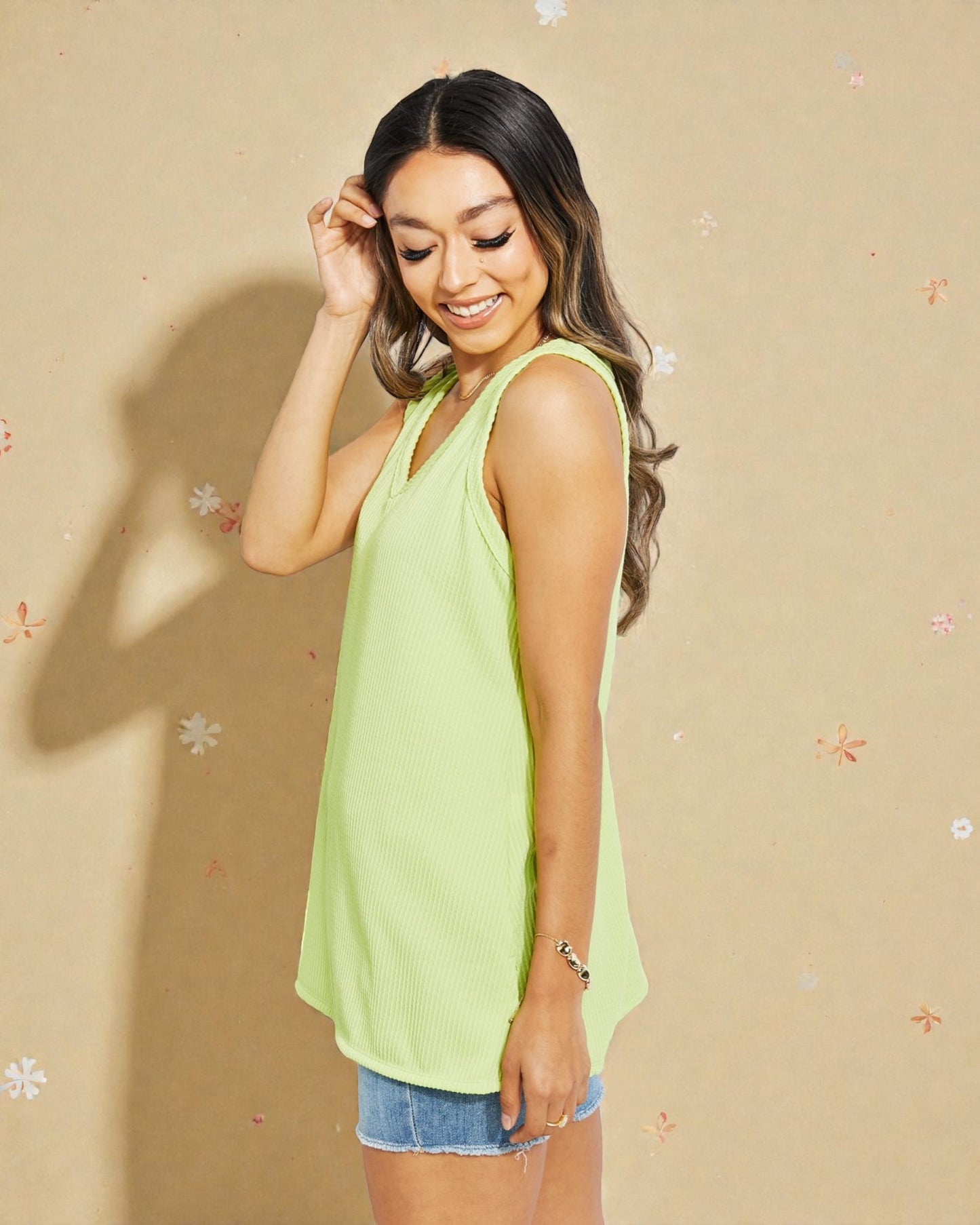 Woman wearing a light green sleeveless top against a beige background