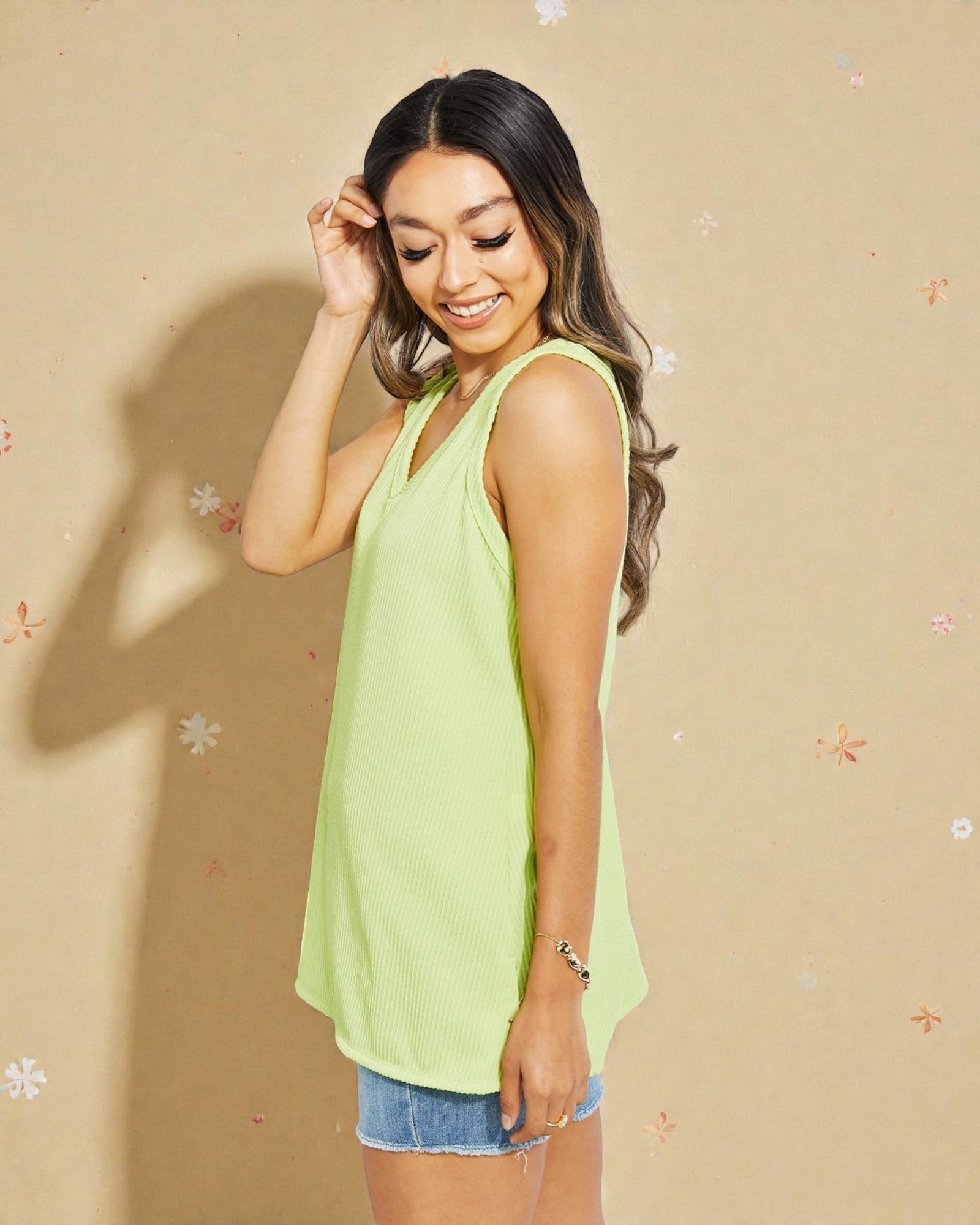 Woman wearing a light green sleeveless top against a beige background