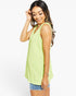 A woman modeling a sleeveless lime green tank top with denim shorts against a plain white studio background.