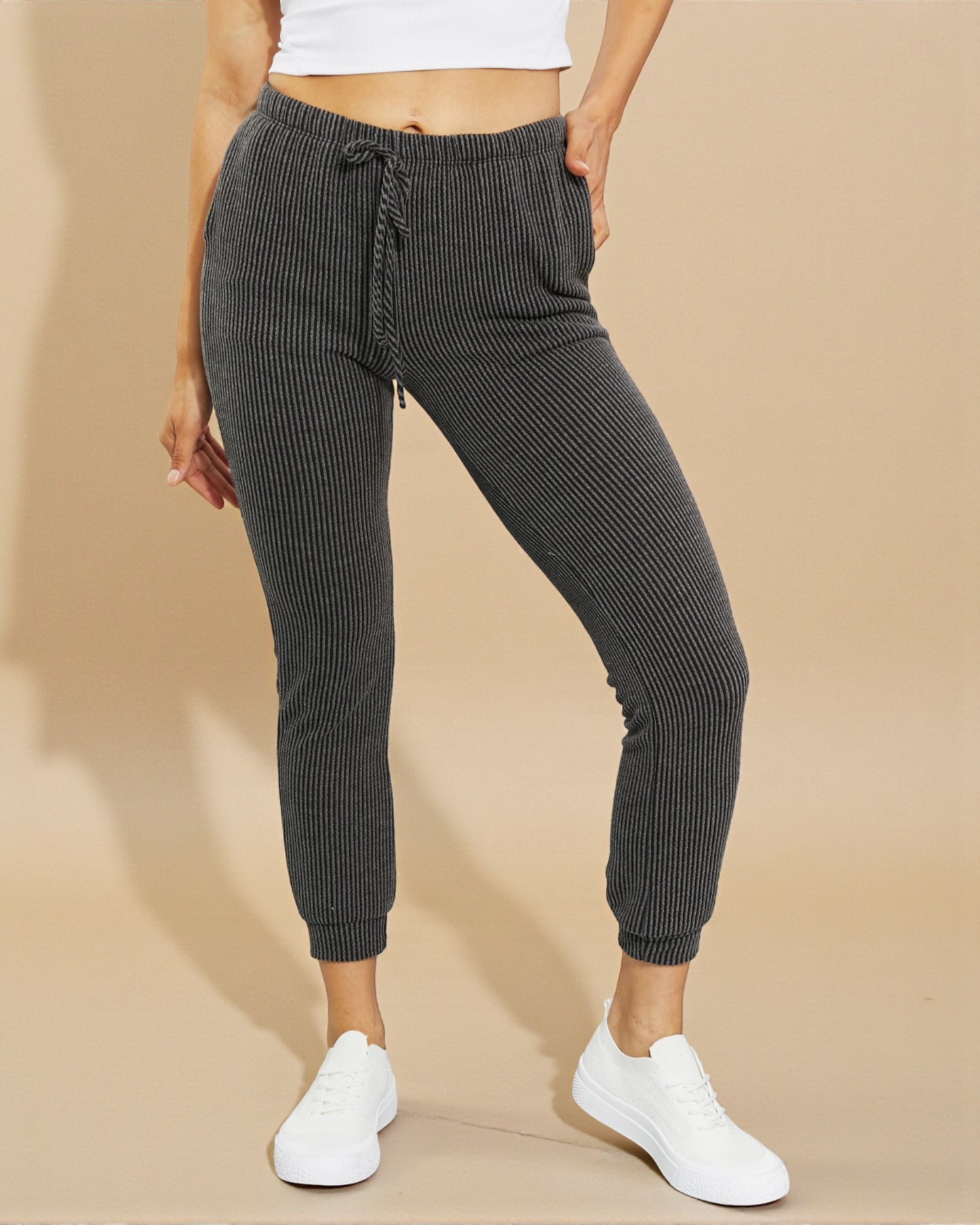 Person wearing gray ribbed jogger pants on a beige background