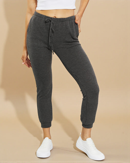 Person wearing gray ribbed jogger pants on a beige background