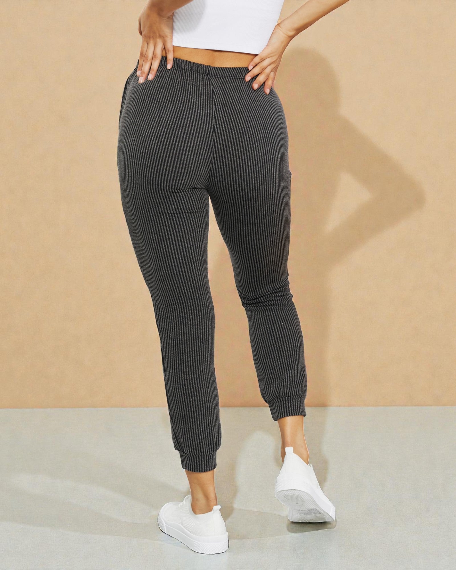 Person wearing gray ribbed jogger pants with a beige background