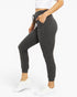 A model wearing dark gray ribbed jogger pants with a drawstring waist and side pockets, paired with a white crop top and white sneakers, shown from the waist down on a white studio background.