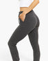 A person wearing dark charcoal gray ribbed leggings with side pockets, shown from the waist down against a plain white studio background.