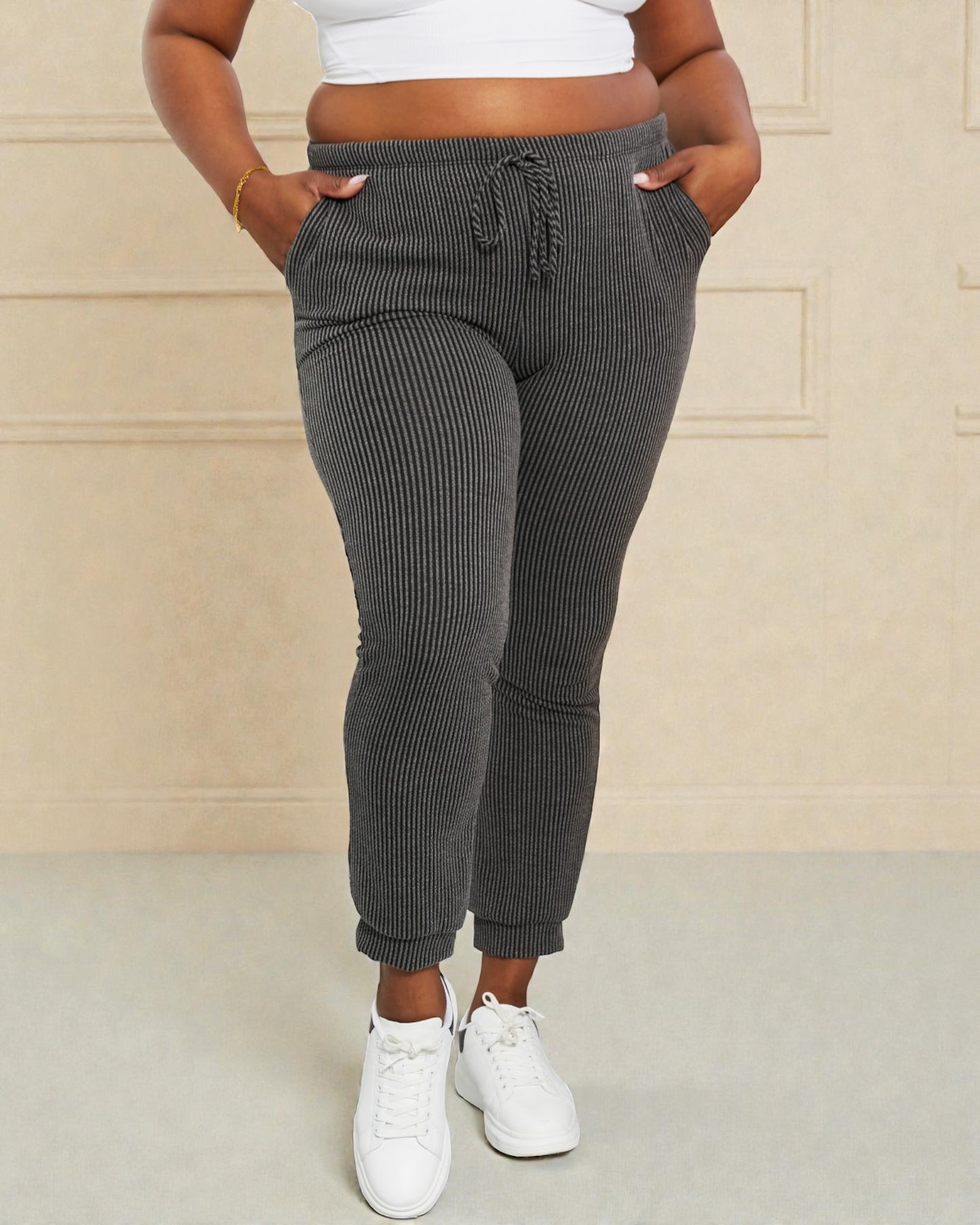 Person wearing gray ribbed jogger pants with a beige background