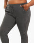 A close-up of a person wearing dark gray and black vertically striped ribbed lounge pants with side pockets and a drawstring waistband, shown against a plain light background.