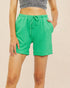 Green shorts worn by a person on a beige background