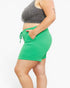 A side-profile view of a person wearing bright green ribbed shorts and a dark gray ribbed crop top against a plain light background.