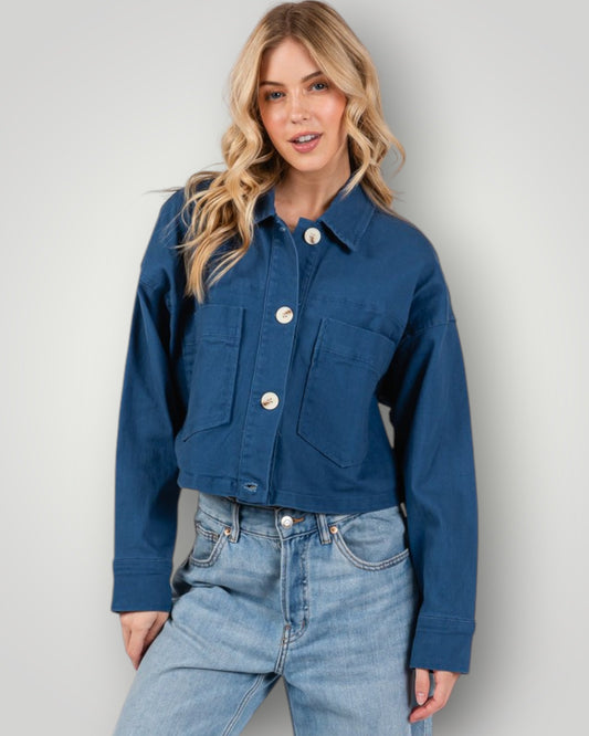 Woman wearing a blue denim jacket and jeans against a plain background