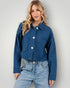 Woman wearing a blue denim jacket and jeans against a plain background