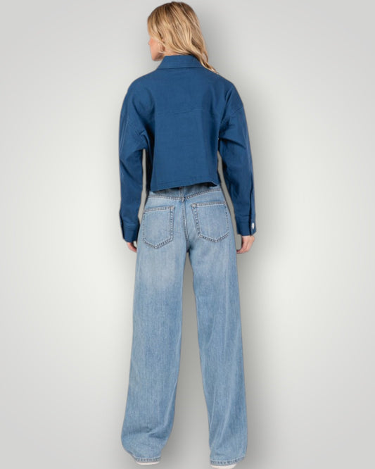 Person wearing a blue denim shirt and light blue jeans on a white background