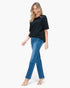 A woman modeling a black short-sleeve top and blue jeans against a plain white background.