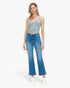 A woman modeling a light gray ribbed camisole crop top and blue flare jeans with white sneakers, standing against a plain white studio background.
