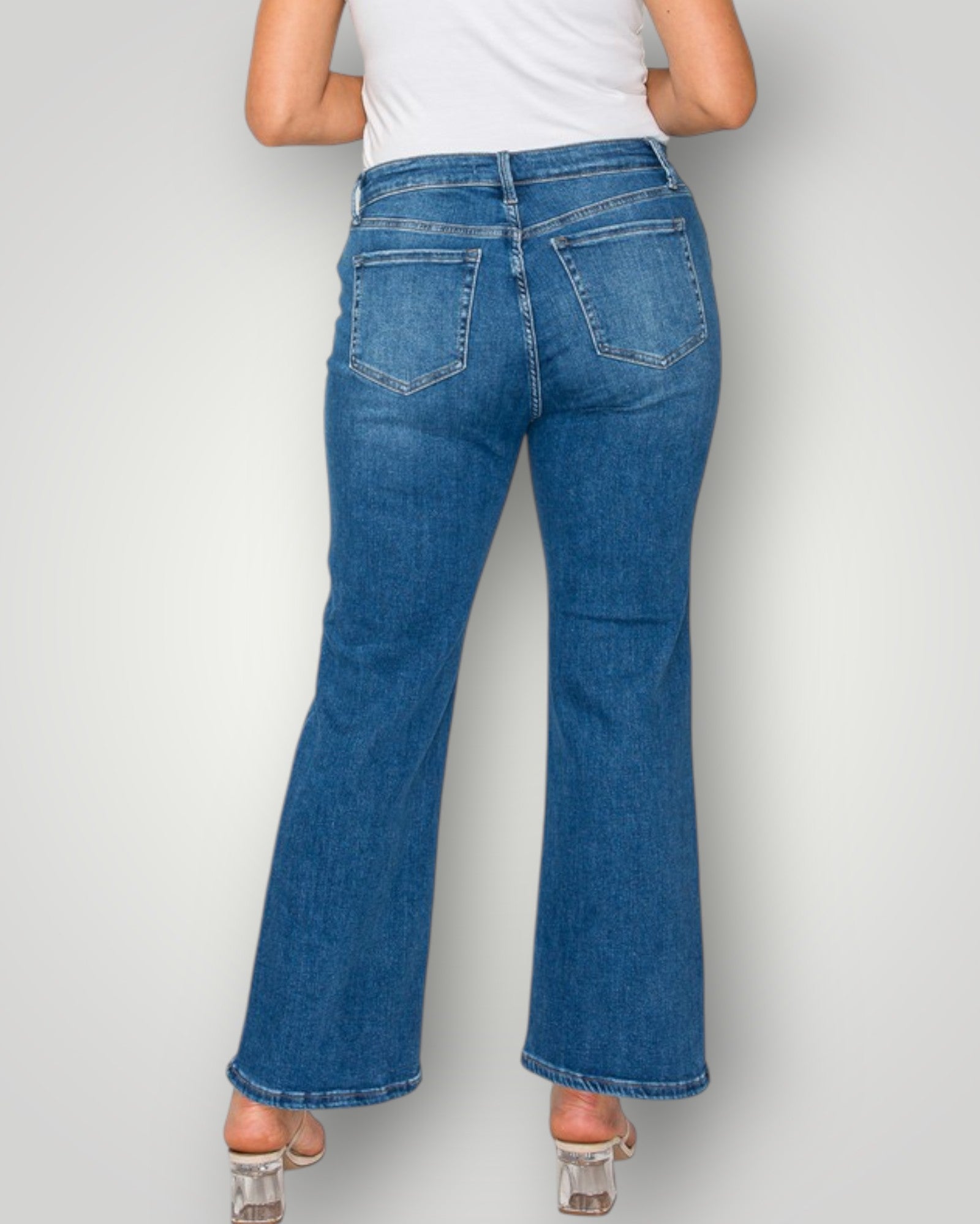 Person wearing blue flared jeans on a plain background