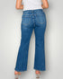 Person wearing blue flared jeans on a plain background
