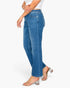 A model wearing a pair of medium-wash blue denim jeans with a straight-to-crew leg fit, paired with a white top and clear block-heel sandals, shown from a side profile against a white studio background.