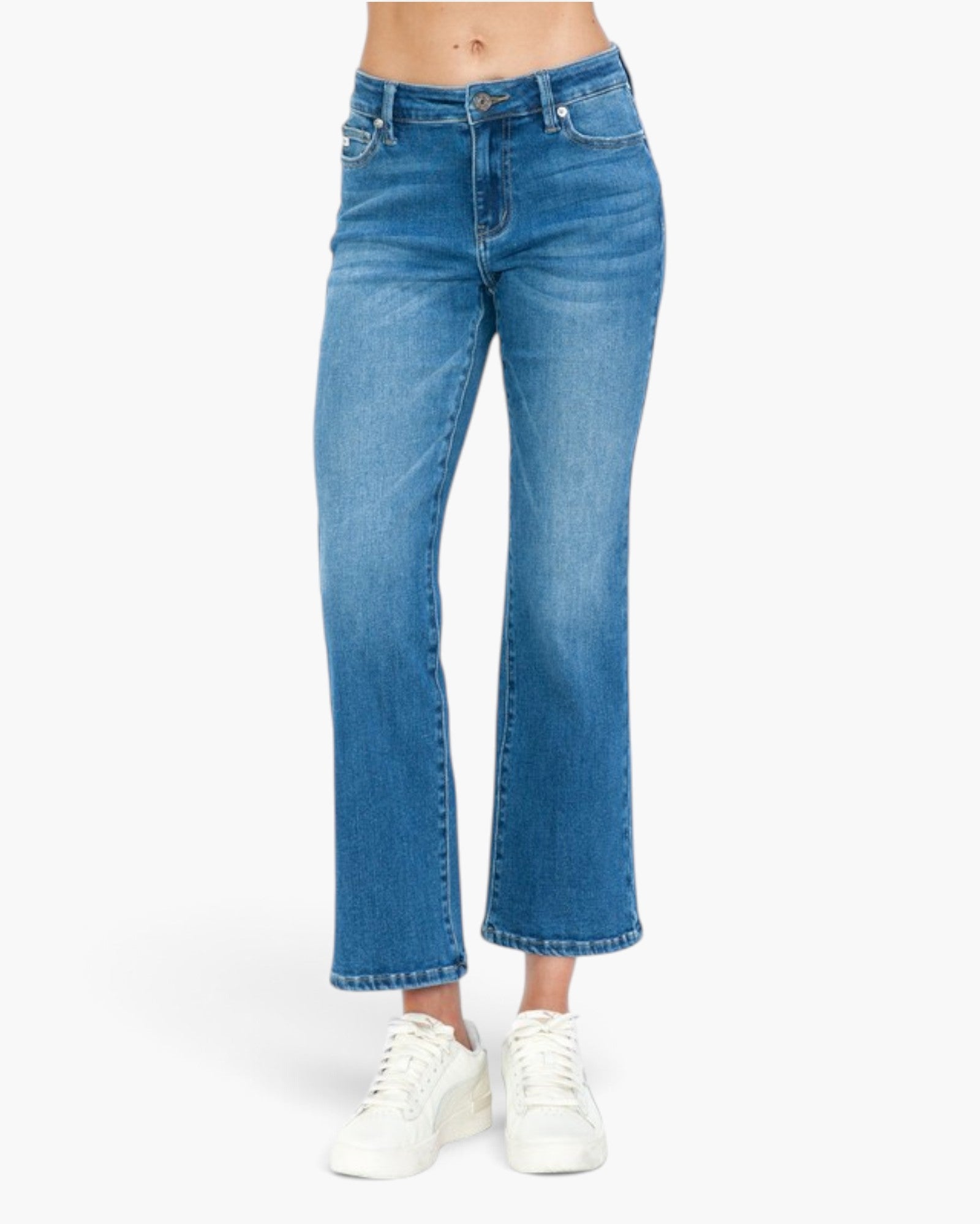 A person wearing medium blue cropped flare jeans with white sneakers, shown from the waist down against a plain light background.