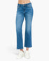 A person wearing medium blue cropped flare jeans with white sneakers, shown from the waist down against a plain light background.