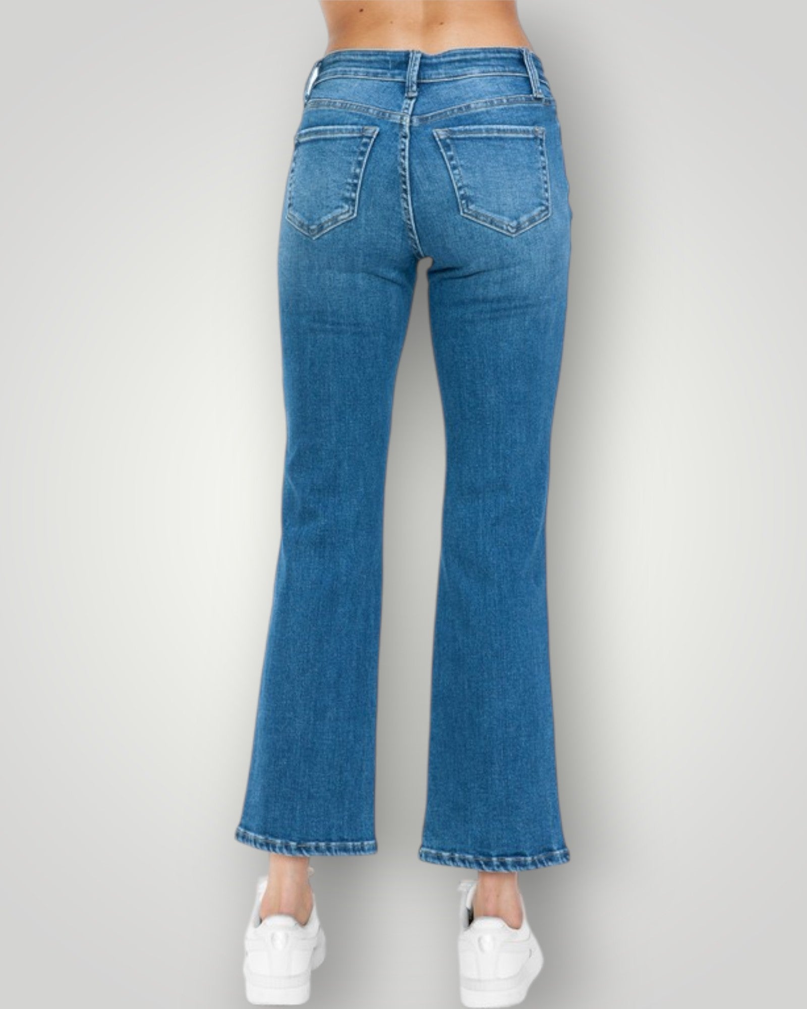 Blue jeans worn by a person on a plain background