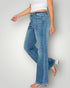 Person wearing blue flared jeans and a white top on a plain background