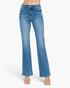 A pair of medium-wash blue denim flare jeans shown on a model from the waist down, paired with clear high-heel sandals against a plain white studio background.