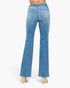 Rear view of a model wearing light blue flare jeans and beige high heels against a plain white background.