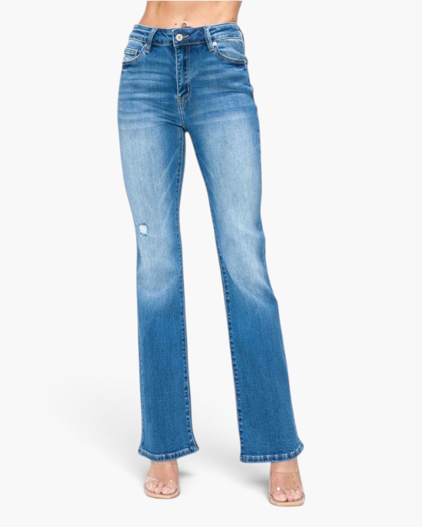 A model wearing a pair of high-waisted, light blue flare jeans with a distressed rip on the left thigh, paired with clear high-heeled sandals against a plain white background.