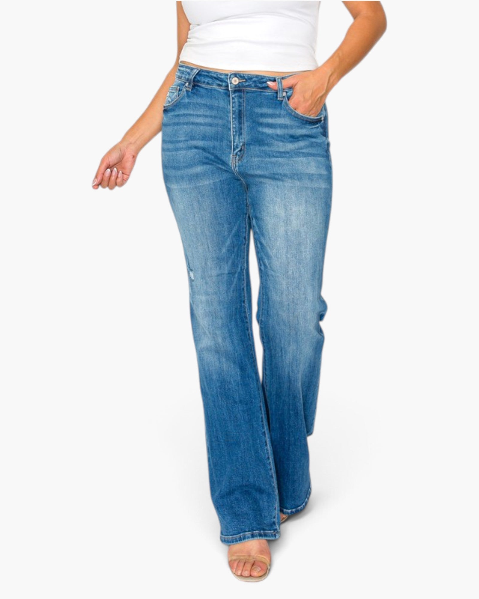 A model wearing a pair of medium-wash blue flare jeans with a white top, shown from the waist down against a plain white background.