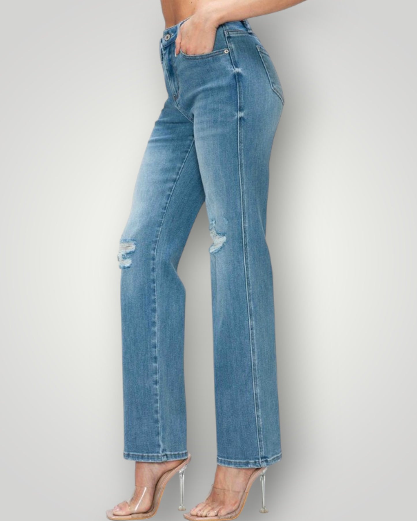 Blue jeans with a slight distressed look worn by a person on a plain background